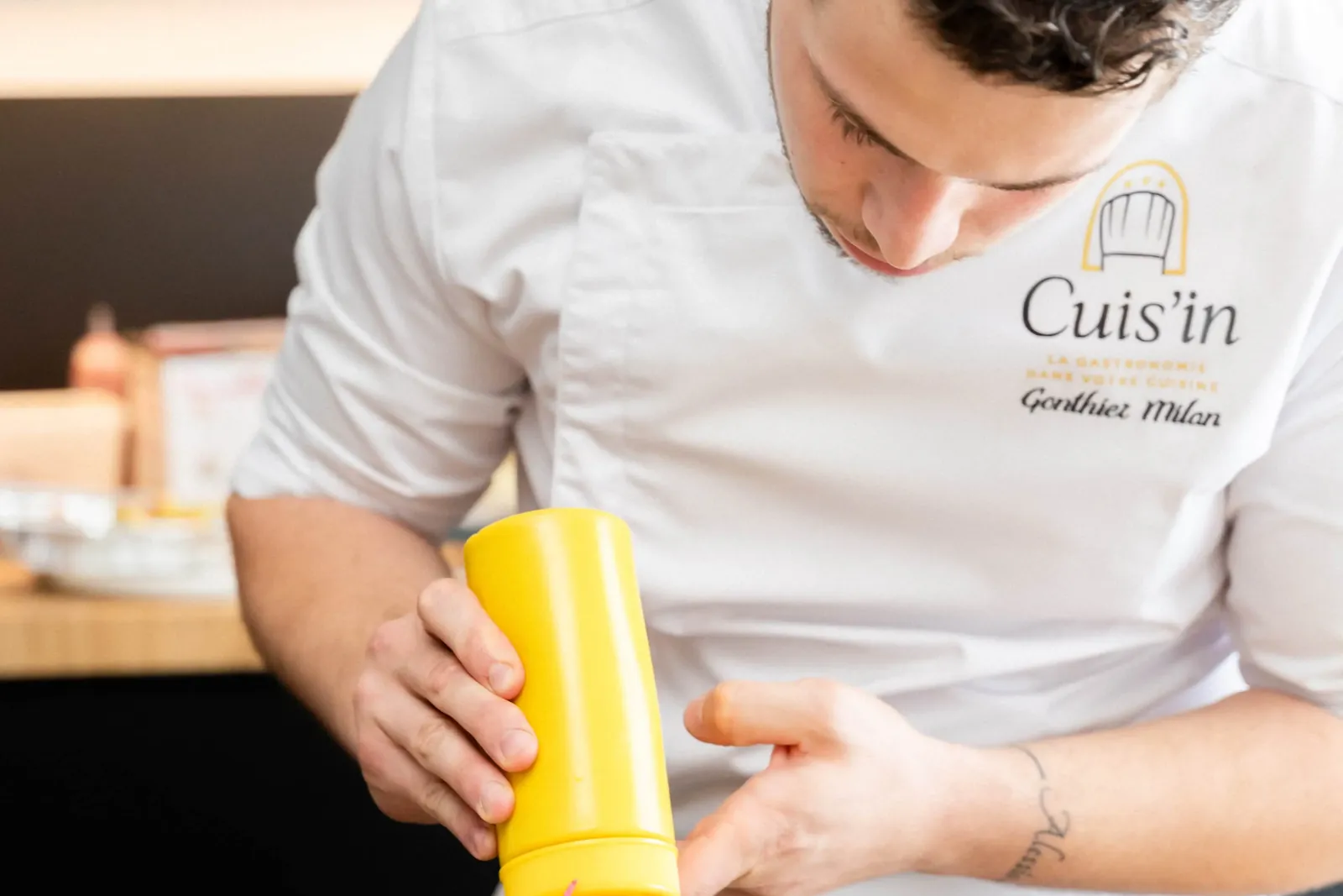 Le chef Milan Gonthier dresse une assiette, en veste Cuis'in