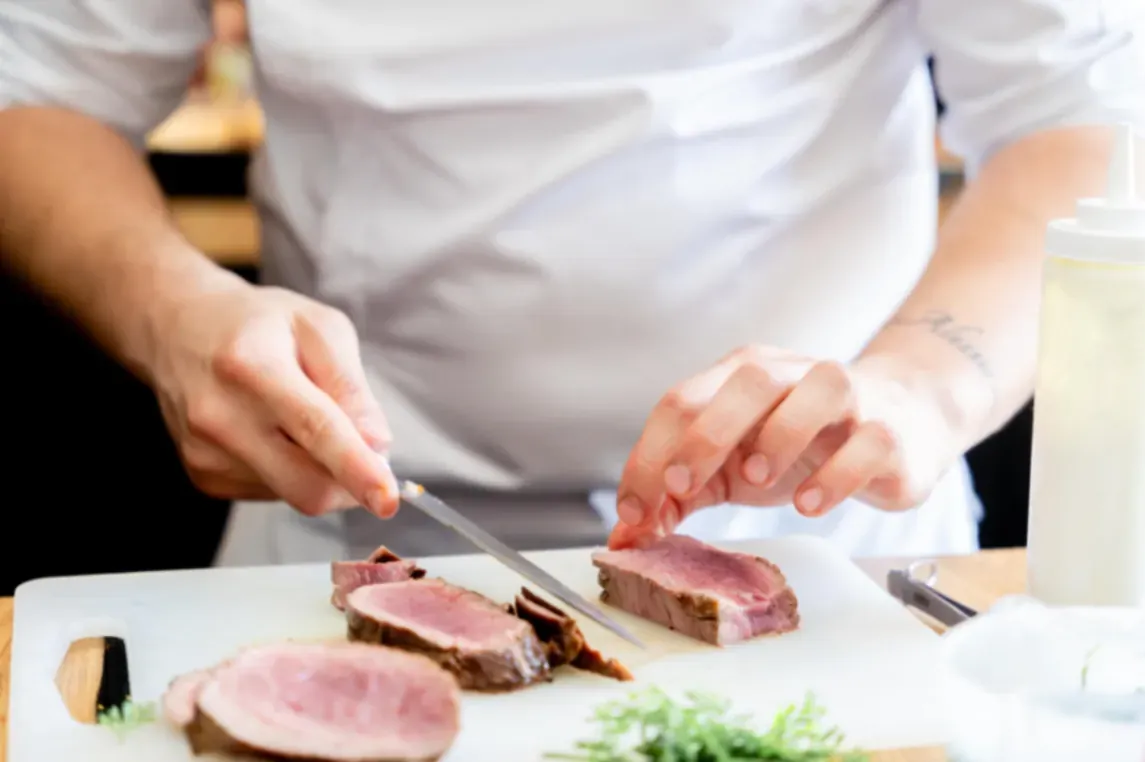 Le chef tranche une viande rôtie